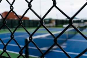 Black chain link sports fence around tennis court