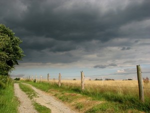 Country road along electric fence with storm clouds