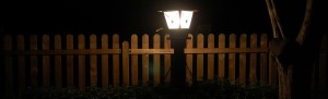 Wood picket fence at night under front yard lantern