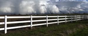 White PVC vinyl fence with rain clouds in background